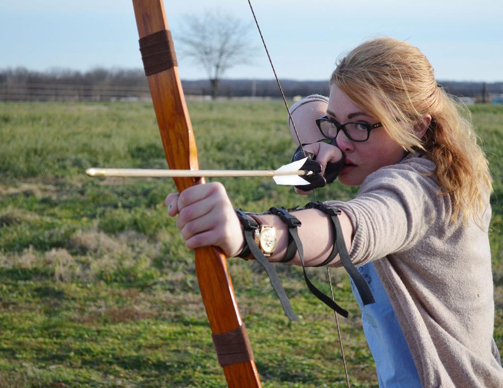 Twisting her body as she pulls back on her six-foot tall traditional English longbow,  junior Kennedy Dold prepares to release a fletched arrow. Photo by Ashley Hocking